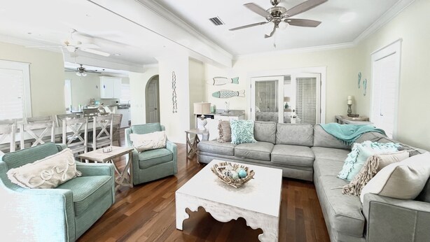 A spacious living room with a grey sofa, two armchairs, a coffee table, and a dining area with a table and chairs. - Gated 30A Home ☀️ 6 Lots from Pool | Easy Walk to Beach ☀️Outdoor Living Area w/ TV (Santa Rosa Beach)