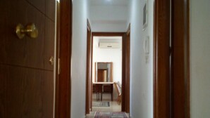 A hallway with a tiled floor leading to a room with a dining table and chairs. - Ikia apartment Ierissos (Ierissos)
