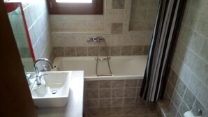A bathroom with a bathtub, a sink, and a toilet. - Ikia apartment Ierissos (Ierissos)