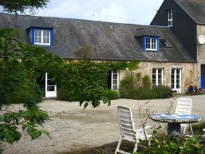 A house with a gravel yard, a white chair, and a small table.