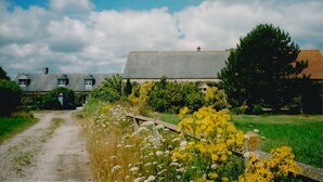 Ett hus på landsbygden med en grusväg som leder fram till det, omgivet av grönska och blommande växter.