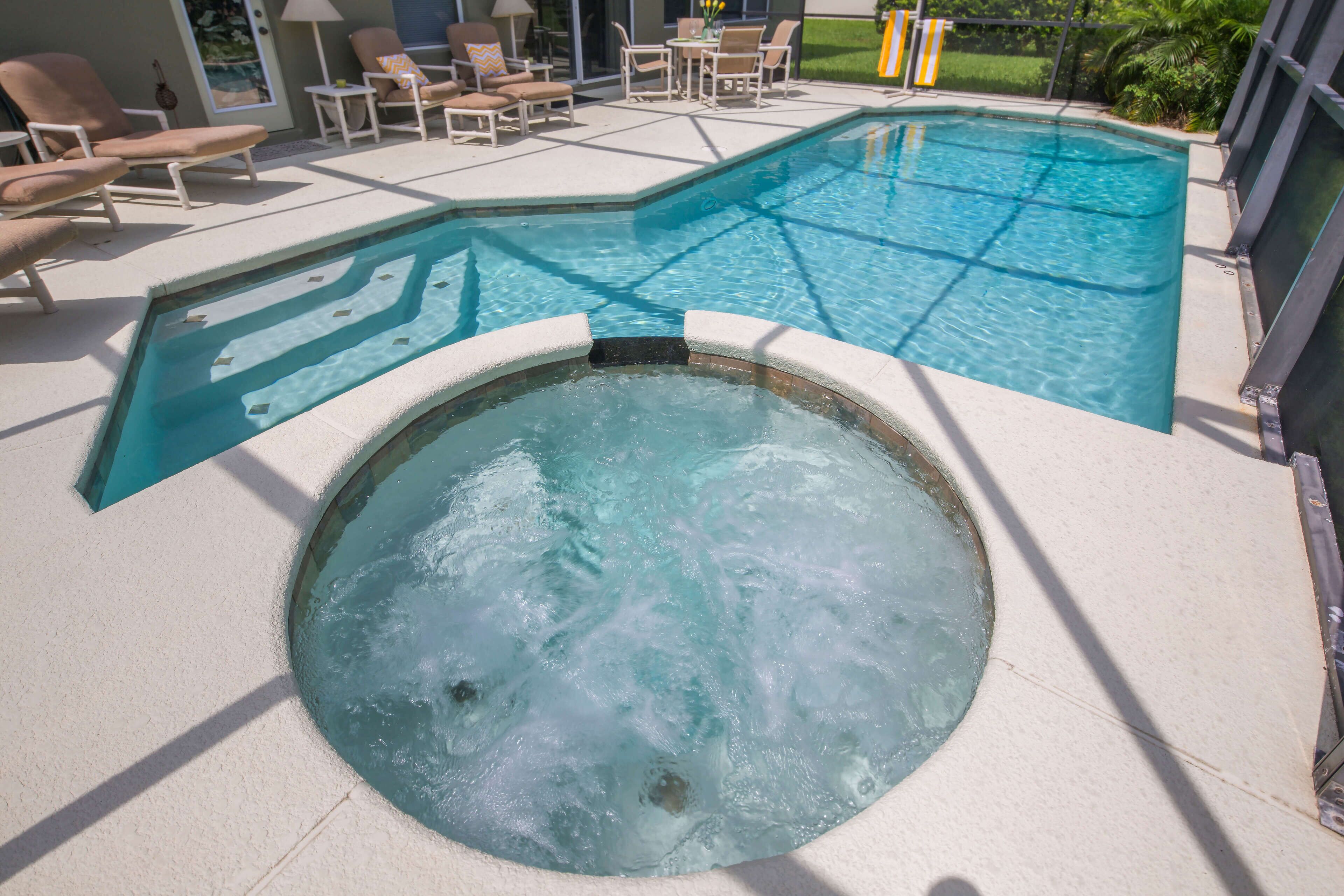 Une piscine avec un jacuzzi, des chaises longues et un espace patio.