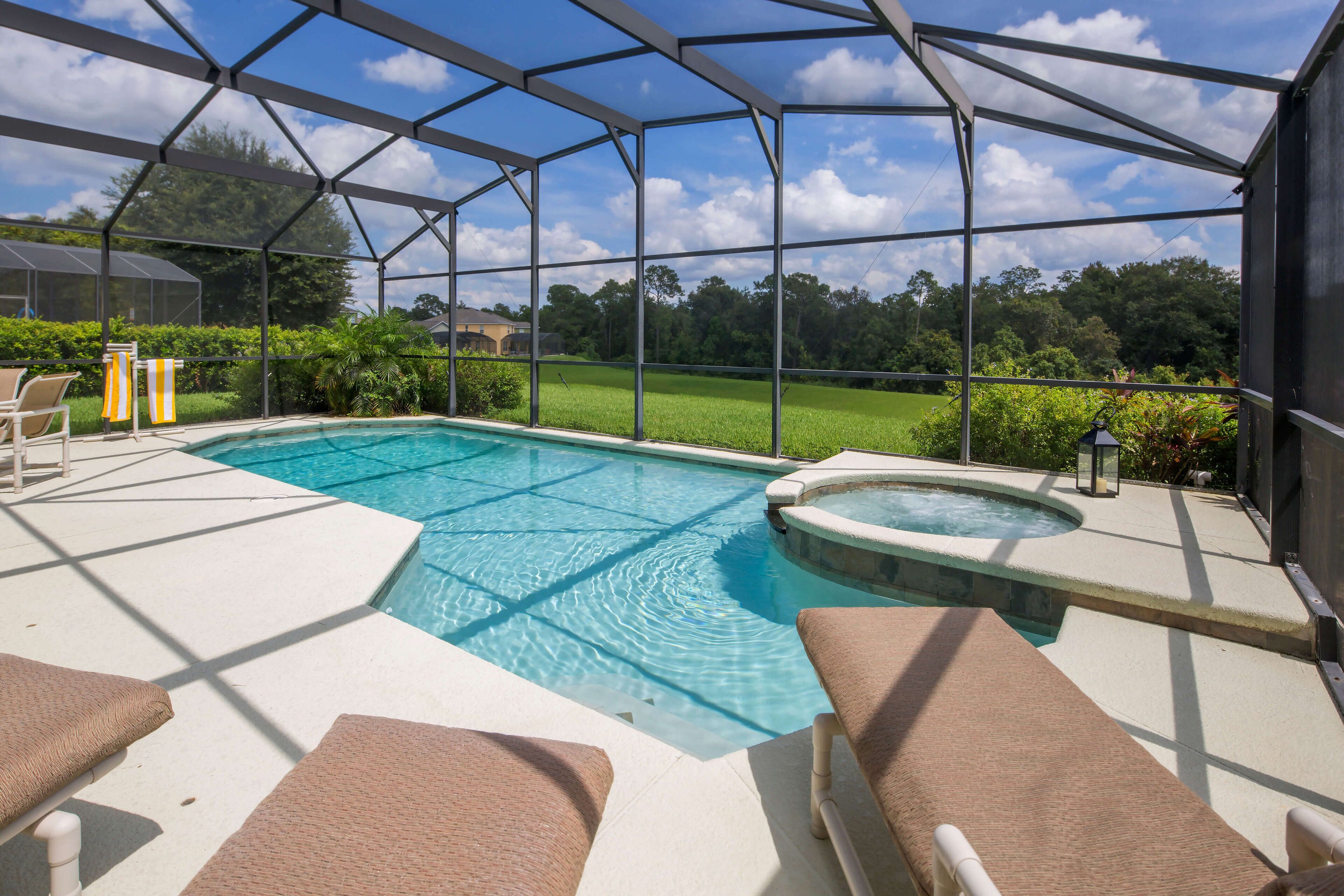 A covered outdoor swimming pool with lounge chairs and a hot tub.