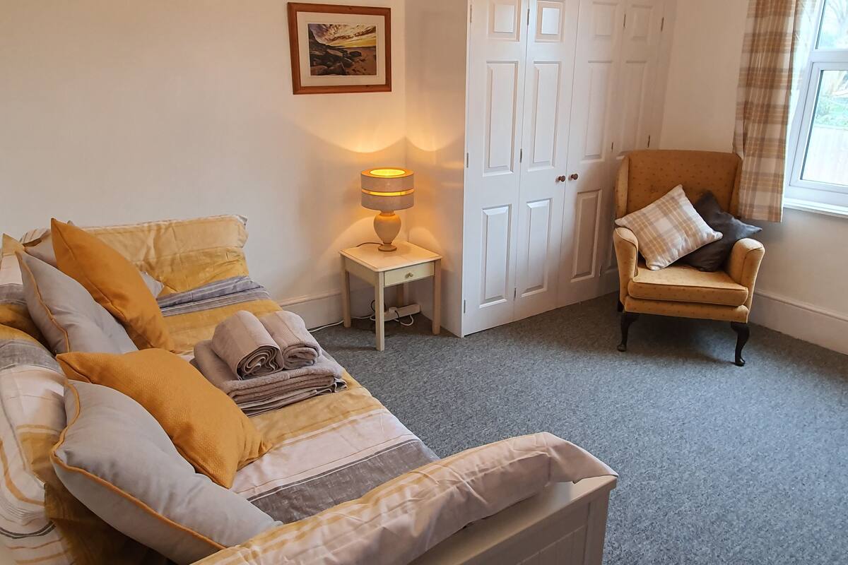 A bedroom with a bed, a chair, a nightstand, a lamp, and a wardrobe.
