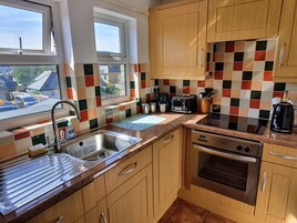 A kitchen with wooden cabinets, a stainless steel sink, a toaster, and a stove.