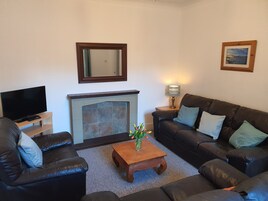 A living room with a fireplace, a television, a sofa, and a coffee table.
