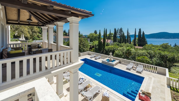 Area piscina con lettini, un gazebo e vista mare e colline.