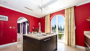 Una cucina moderna con isola centrale, un'ampia finestra con tende e vista sull'esterno.