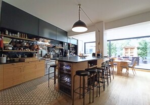 A modern kitchen with a central island, bar stools, and a large window offering a view of the outdoors.