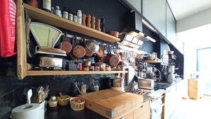 Una cocina moderna con armarios de madera, encimera negra y diferentes utensilios y electrodomésticos.