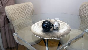 Una habitación moderna con una mesa de vidrio, dos sillones acolchados y un plato decorativo con dos objetos esféricos.