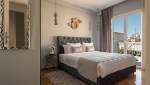 Un dormitorio moderno con una cama grande, una mesita auxiliar pequeña y un espejo.