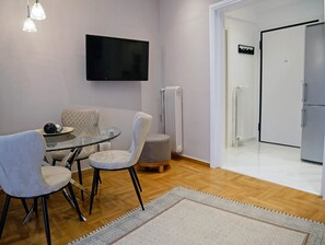 A modern living room with a glass table, two chairs, a flat-screen TV, and a white door. - Penthouse with Acropolis view (Athina)