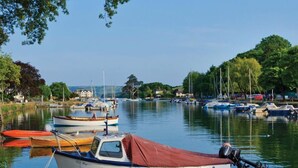Ein ruhiger Hafen mit mehreren vertäuten Booten, umgeben von viel Grün und blauem Himmel.