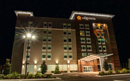 A La Quinta hotel with a modern facade, multiple windows, and a well-lit entrance.
