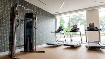 A gym with treadmills, a weight machine, and large windows.