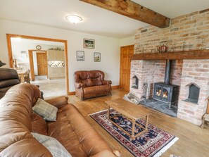 A cozy living room with a leather sofa, a wooden coffee table, and a fireplace. - Pentrego Isaf (Meifod)