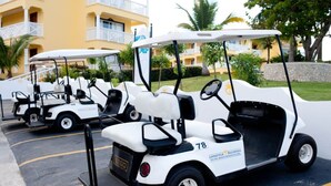 A row of golf carts parked in a lot with a yellow building in the background. - BEAUTIFUL 3-4 BEDROOM VILLA, PRIVATE POOL, V.I.P. ACCESS $200 per night (Puerto Plata)