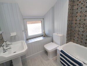 Un baño con ventana, inodoro, lavamanos y bañera.