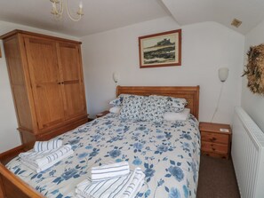 Un dormitorio con cama de madera, mesita de noche, armario y un cuadro en la pared.