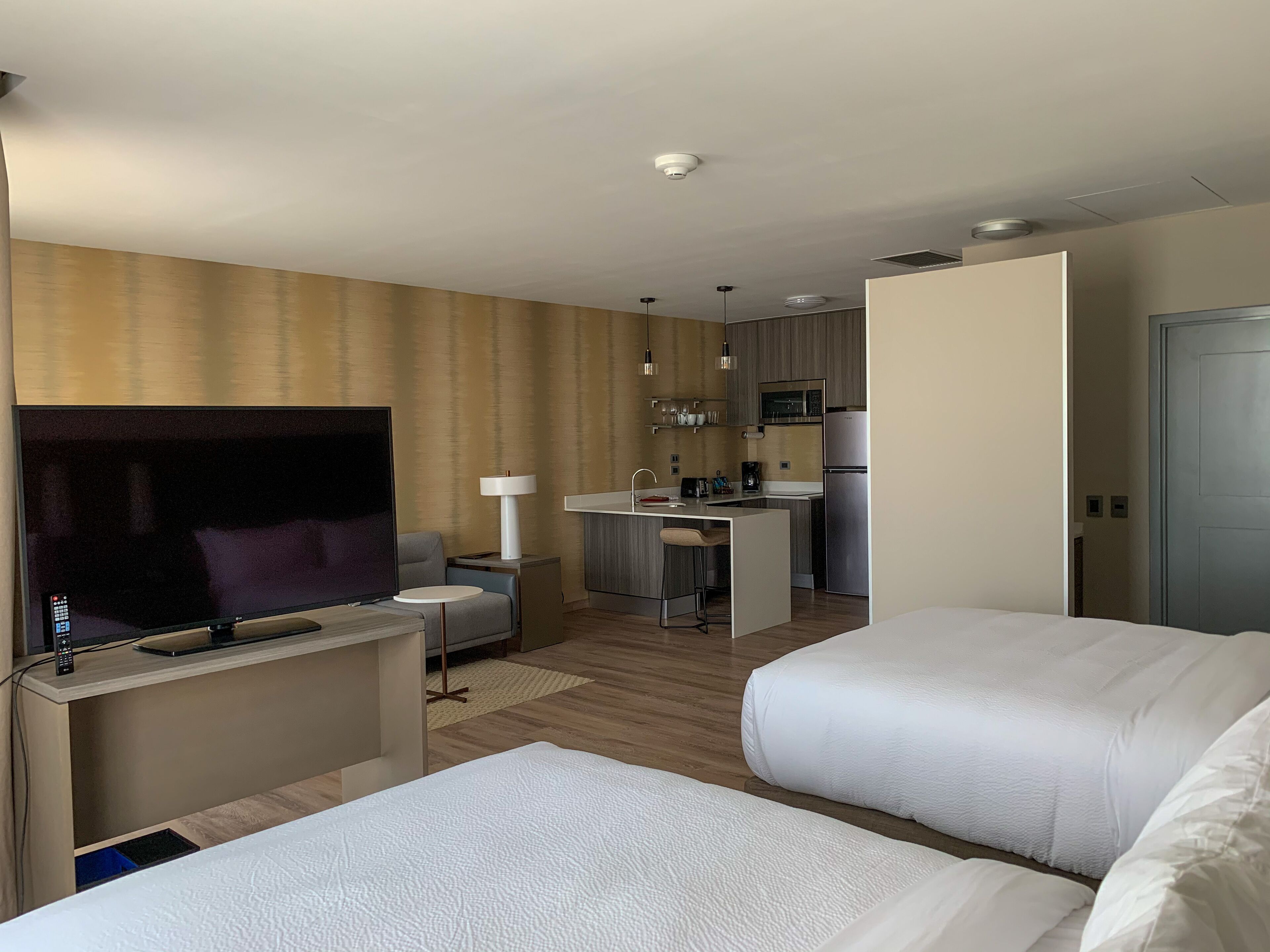 Habitación de hotel con televisión, dos camas, una kitchenette pequeña y un baño.