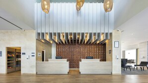 Un espace d’accueil moderne avec un comptoir d’accueil en bois, un mur décoré de motifs et trois lampes suspendues.