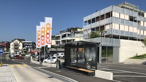 Eine moderne Stadtstraße mit Bushaltestelle, Gebäuden und einer Fußgängerquerung.