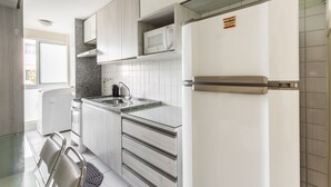 A modern kitchen with white cabinets, a built-in microwave, and a stainless steel refrigerator. - Palm Village Acqua (Ipojuca)
