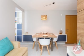 Un espace repas moderne avec une table en bois, des chaises blanches et un luminaire suspendu.