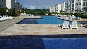 A swimming pool with lounge chairs and a tiled deck area. - Palm Village Acqua (Ipojuca)