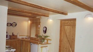Eine Küche mit Holzbalken, einem Spülbecken, einer Uhr und einer Tür.