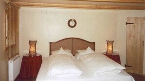 Ein Schlafzimmer mit einem Holz-Kopfteil, einem Bett mit weißen Bettwäsche, zwei Nachttischen mit Lampen und einer Holztür.
