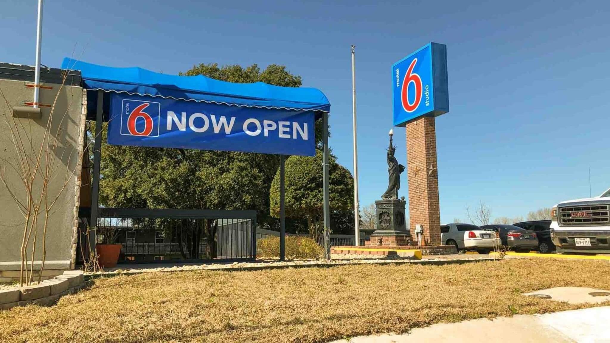 A motel with a blue canopy and a prominent '6' sign, indicating its name.