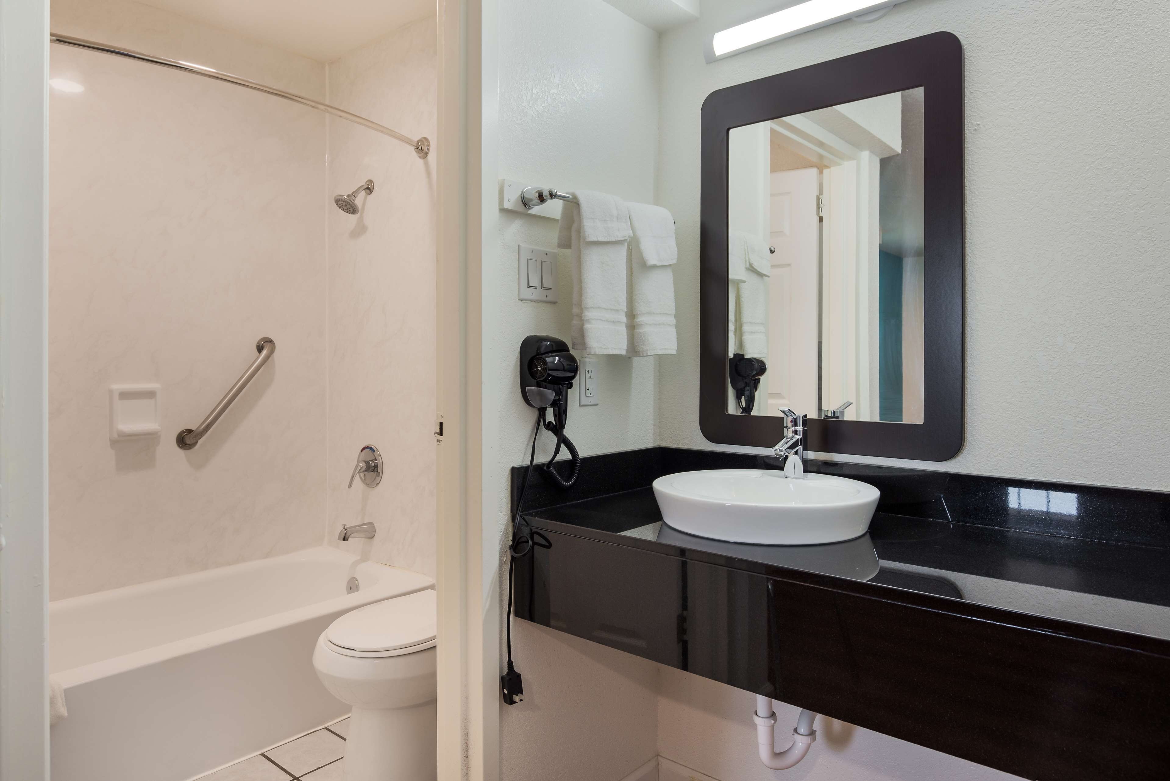 A bathroom with a bathtub, toilet, and a sink with a large mirror above it.