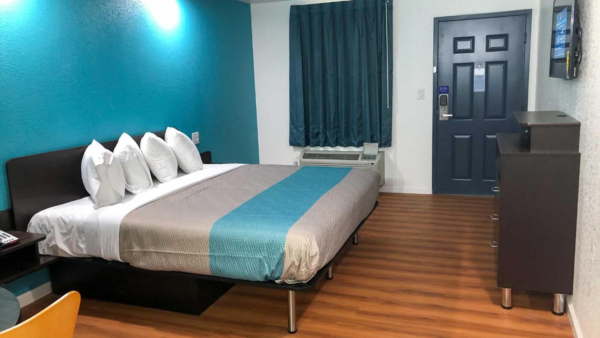 Una habitación de hotel con cama, escritorio, silla, armario y puerta.