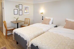 Une chambre avec deux lits, un bureau et une chaise. Des certificats encadrés sont accrochés au mur, et une lampe est fixée au mur.