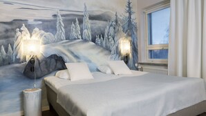 Un dormitorio con una cama, dos lámparas de noche, un mural en la pared y una ventana con cortinas.