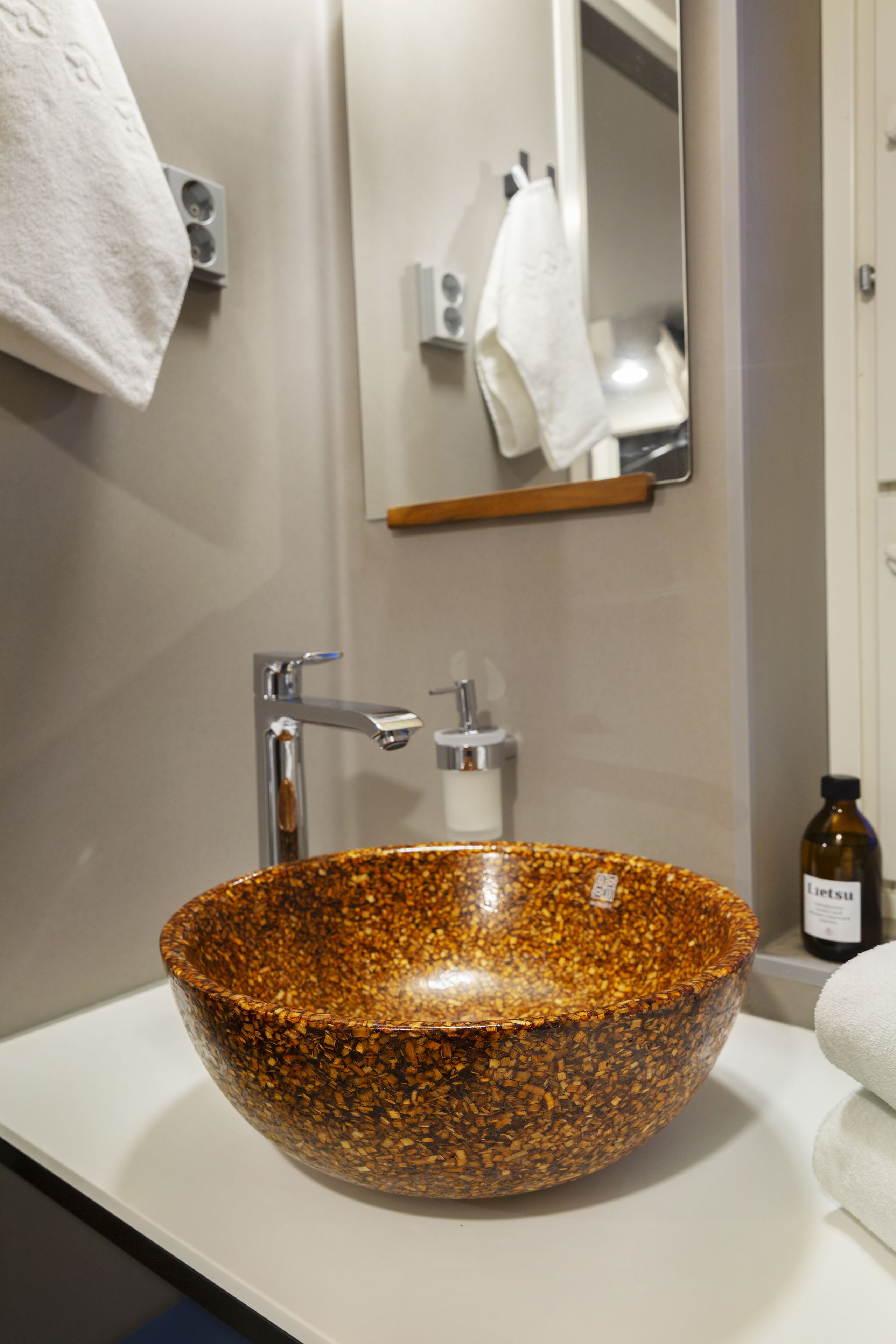 Une salle de bain avec un grand lavabo en céramique à motifs, un robinet moderne et un miroir au-dessus du lavabo.
