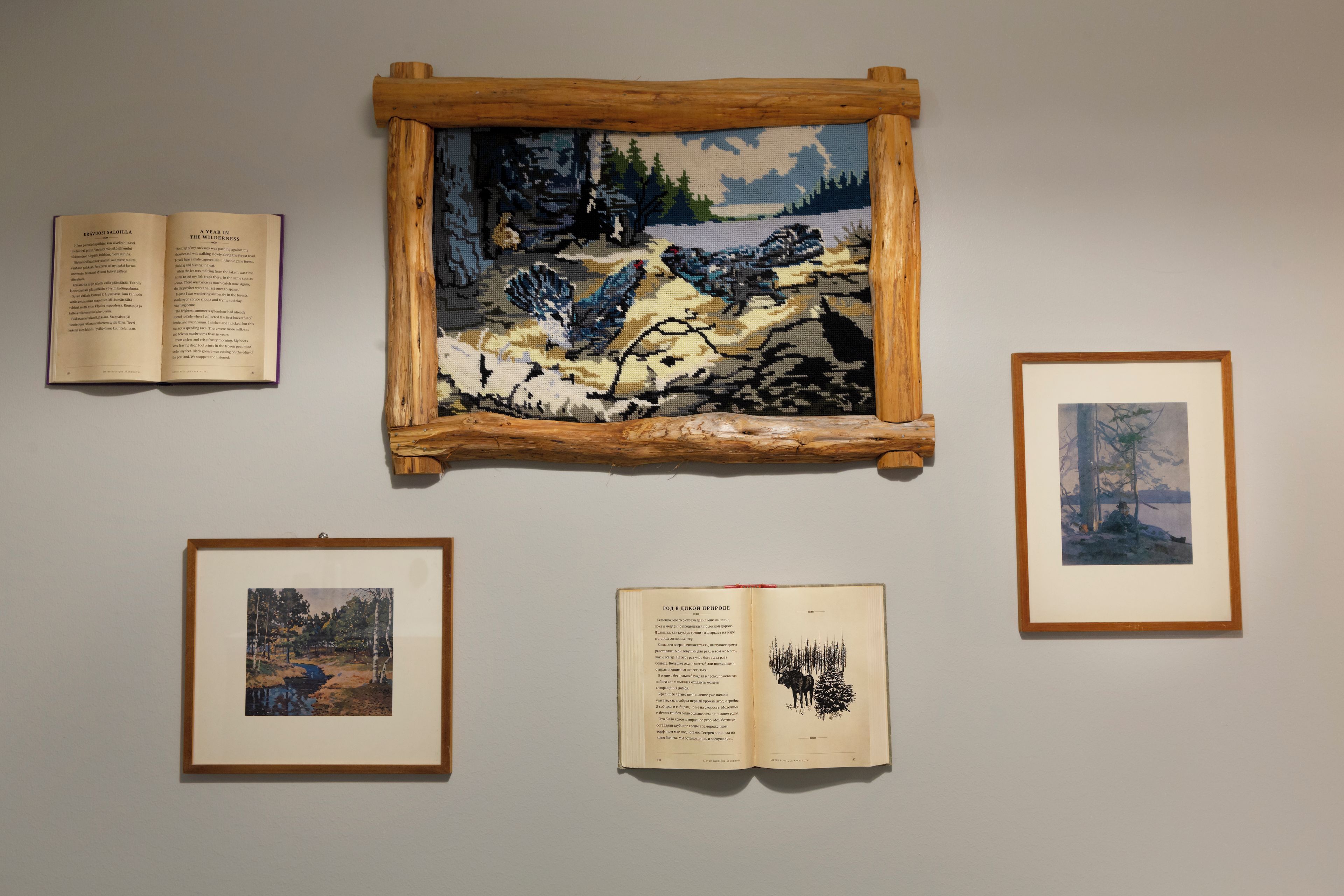 A framed painting on a wall with books and framed pictures below it.