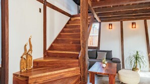 Ein geräumiges Zimmer mit einer Holztreppe, einem Sofa, einem Couchtisch und einer kleinen Pflanze.