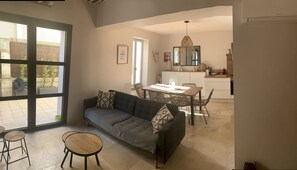 Un salon moderne avec un canapé, deux tables rondes et un coin repas avec des chaises.