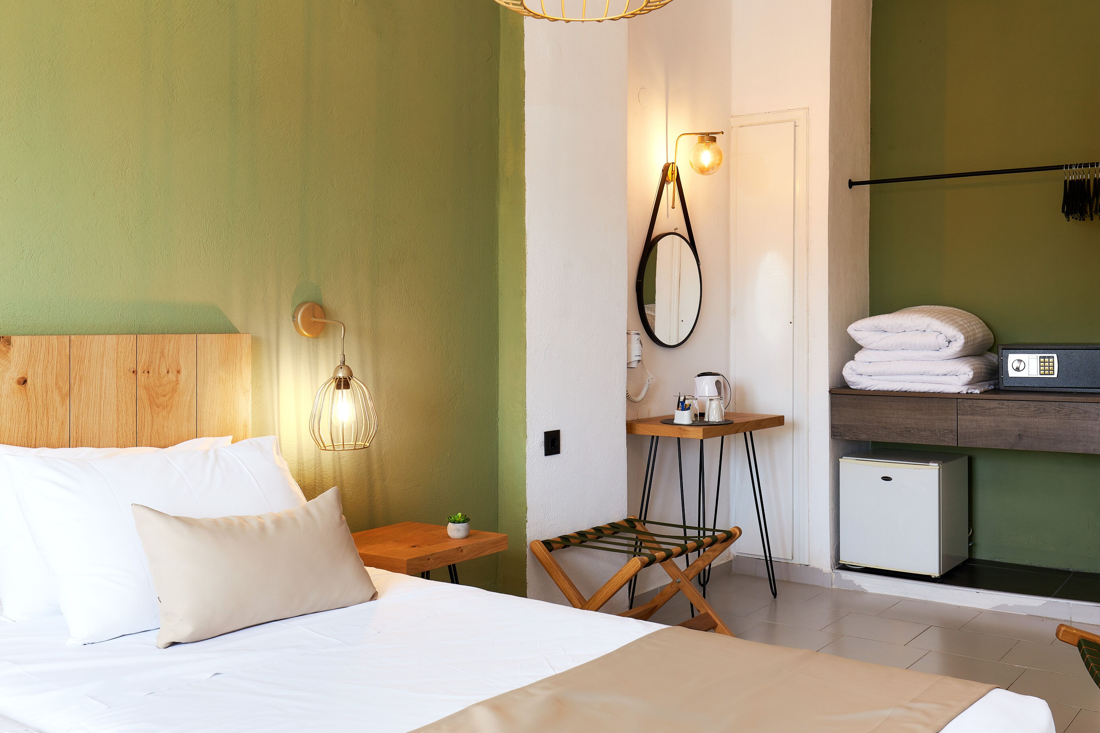 A bedroom with a bed, bedside table, lamp, and a small table with a plant.