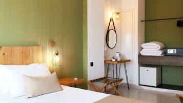 A bedroom with a bed, bedside table, lamp, and a small table with a plant.