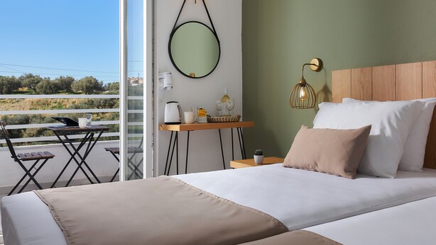 A bedroom with a bed, bedside table, and a view of the outdoors. - Charm Hotel Hersonissos (Hersonissos)