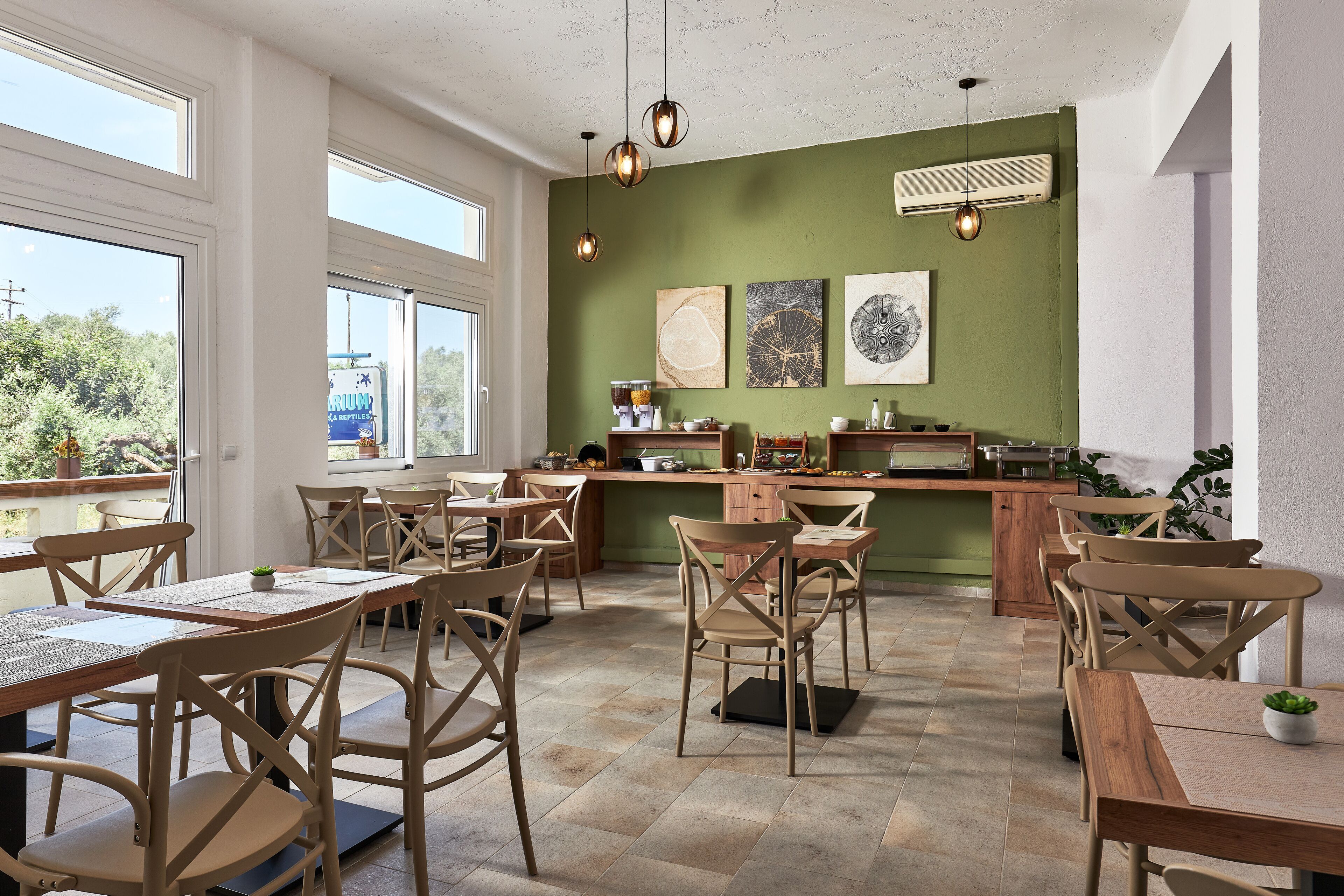 A dining area with wooden tables and chairs, a green accent wall, and artwork.