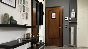 A modern hallway with a marble floor, a wooden door, and a wall-mounted TV.