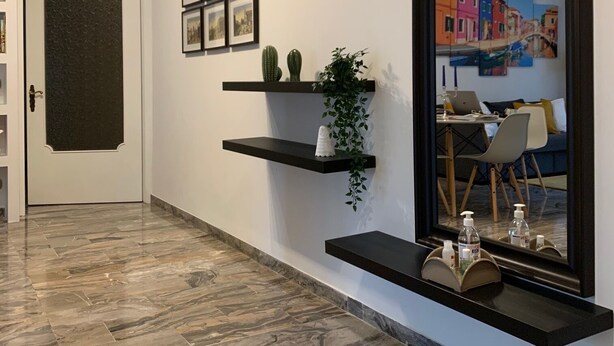 A hallway with a large mirror, black floating shelves, and framed pictures on the wall.