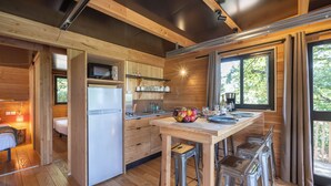 Cocina compacta con alacenas de madera, un refrigerador y una zona de comedor con taburetes.