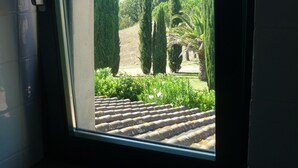Una ventana con vistas a un jardín con setos bien cuidados y un tejado de tejas.