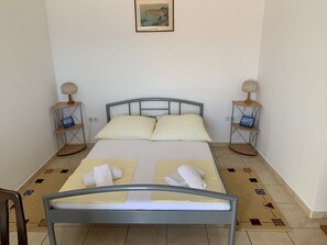 A neatly arranged bedroom with a bed, two bedside tables, a chair, and a rug. - Apartment 1 with pool and amazing sea view (Lokva Rogoznica)
